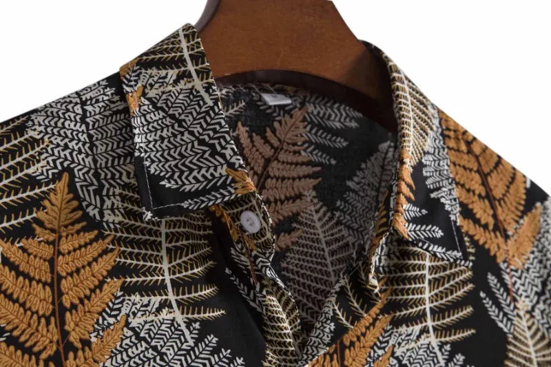 Camisa Manga Curta Marcanzzi Marbella MZ581 com estampa tropical de folhas em preto, branco e dourado, tecido leve, caimento confortável e versátil.