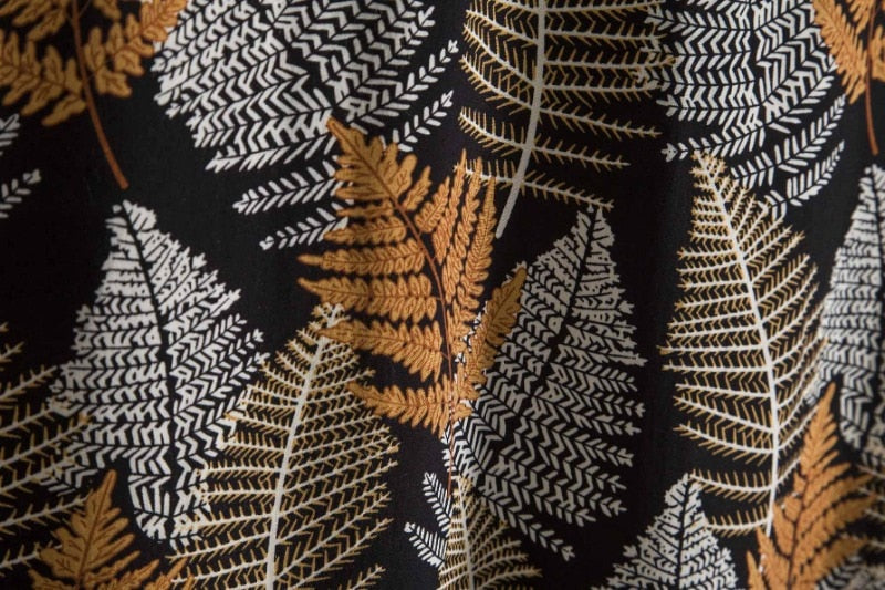 Camisa Manga Curta Marcanzzi Marbella MZ581 com estampa tropical de folhas em preto, branco e dourado, tecido leve, caimento confortável e versátil.